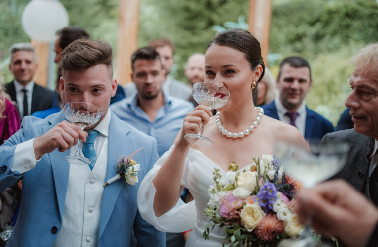 Přípitek novomanželů obklopených svatebčany