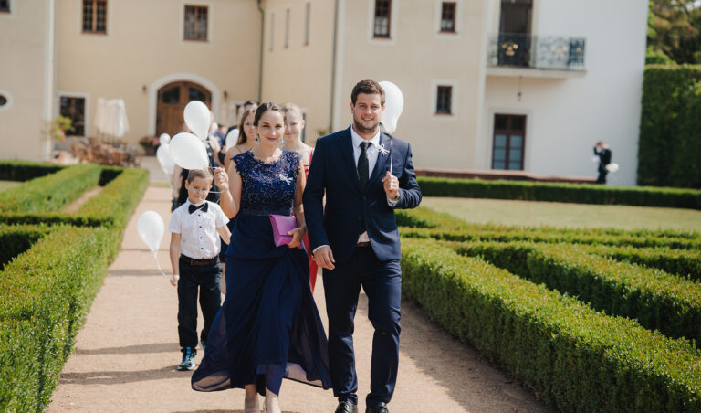 Svatebčané přicházejí zámeckou zahradou